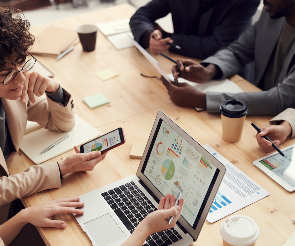 group of people in a conference call holding mobiles in their hands and looking at dashboard in laptop