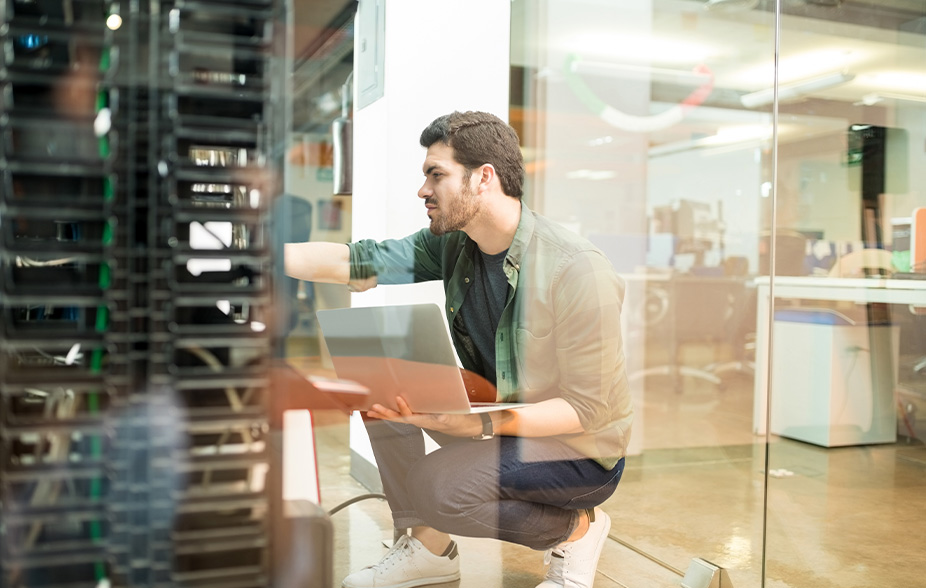 person kneeling down in front of a server rack